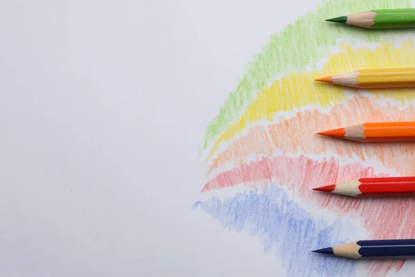 Colorful pencils with swatches on white background, top view