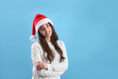 Açık mavi arka planda Noel Baba şapkası takan güzel bir kadın. Metin için boşluk