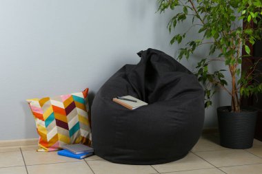 Black cozy bean bag chair near light grey wall in room