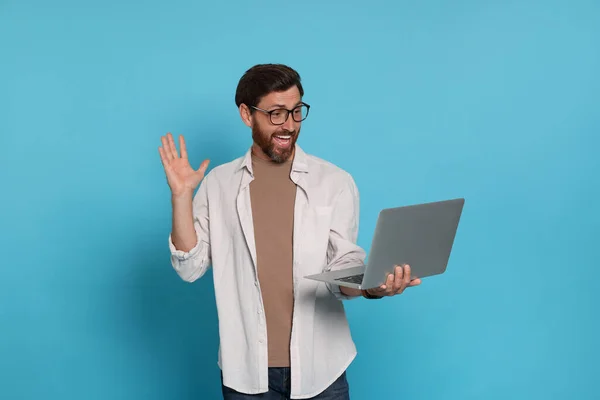 Handsome man with laptop on light blue background