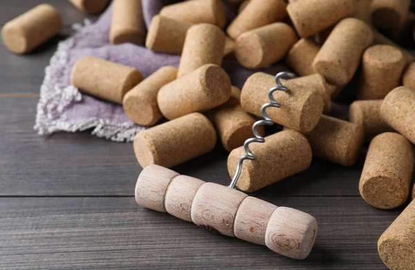 Corkscrew and wine bottle stoppers on wooden table, closeup