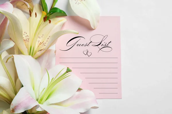 Guest list and beautiful flowers on white background, closeup view