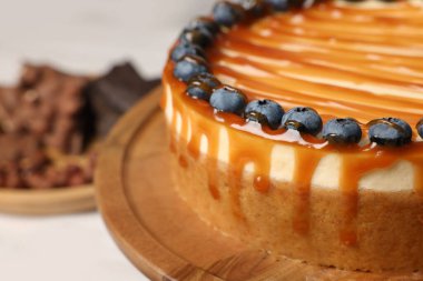 Delicious cheesecake with caramel and blueberries, closeup. Space for text