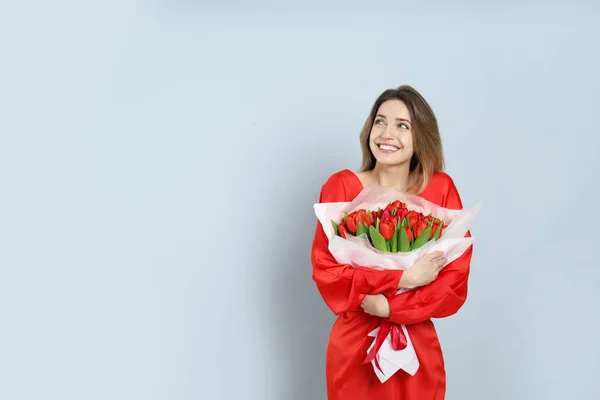 ライトグレーの背景に赤いチューリップの花束を持つ幸せな女性 テキストのためのスペース 3月8日 — ストック写真