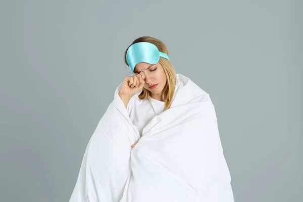 若いです女性で寝マスクラップで柔らかい毛布で灰色の背景 — ストック写真