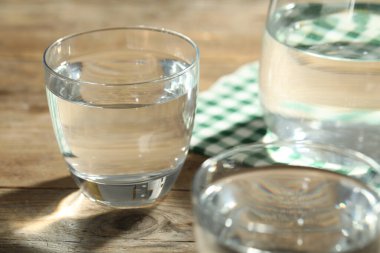 Ahşap masada bir bardak su. Tazeleyici içecek.