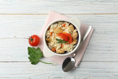Beyaz ahşap masada servis edilen leziz tavuklu risotto.