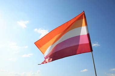 Bright lesbian flag fluttering against blue sky