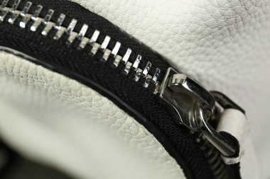 White leather fabric with zipper as background, closeup view
