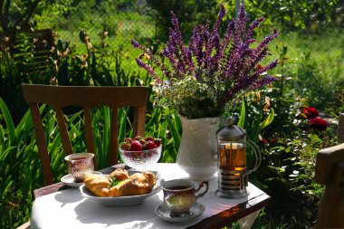 Beautiful bouquet of wildflowers on table served for tea drinking in garden