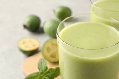 Fresh feijoa smoothie in glass on table, closeup view
