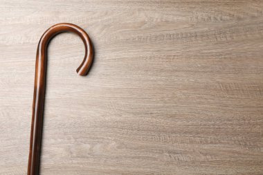 Elegant walking cane on wooden table, top view. Space for text