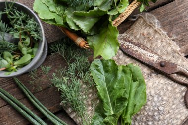 Flat lay composition with different herbs, rusty scissors and burlap fabric on wooden table
