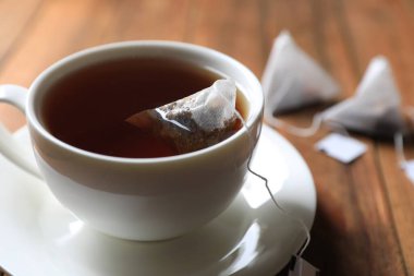 Tea bag in cup on wooden table, closeup