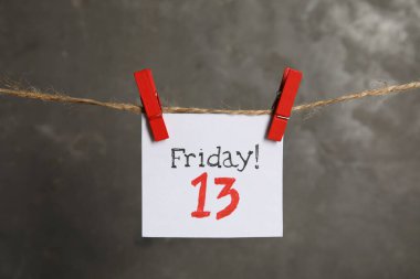 Cuma günü yazılı kağıt! Gri arka planda sicimde 13 asılı duruyor. Kötü şans batıl inanç.