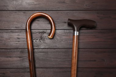 Different elegant walking canes on wooden table, flat lay