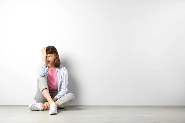 Unhappy Young Girl Sitting Floor White Wall Space Text —  Fotos de Stock