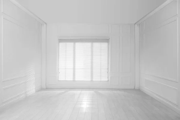 Empty room with white walls, large window and wooden floor