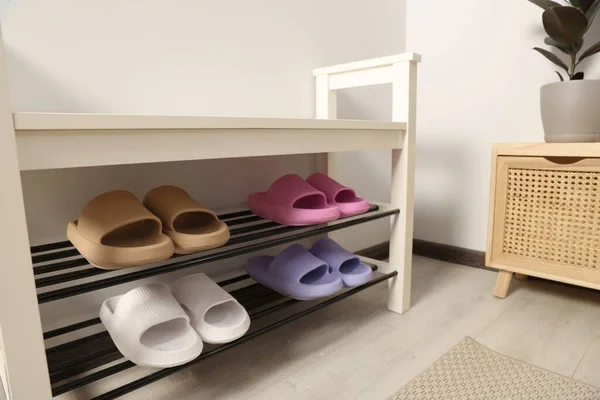 Storage bench with pairs of rubber slippers in room