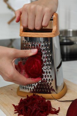 Mutfak tezgahında taze pancar rendeleyen kadın, yakın plan.