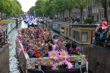 AMSTERDAM, NETHERLANDS - AUGUST 06, 2022: Many people in boats at LGBT pride parade on river