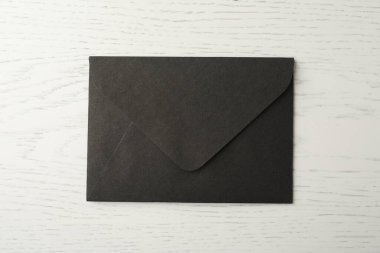 Beyaz ahşap zemin üzerinde siyah kağıt zarf, üst görünüm