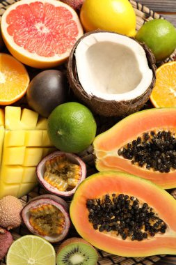 Fresh ripe papaya and other fruits on wicker mat, closeup view