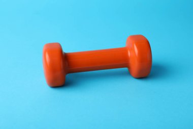 Stylish dumbbell on light blue background, closeup