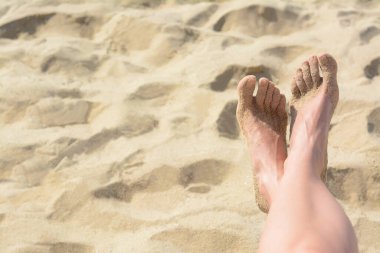 Woman resting on sandy beach, closeup of feet. Space for text