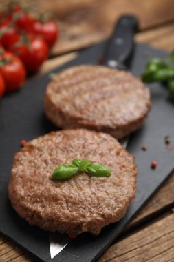 Ahşap masada servis edilen leziz ızgara hamburger köfteleri, yakın plan.