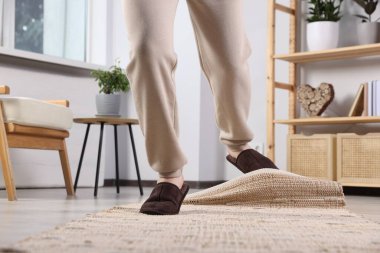 Man tripping over rug at home, closeup