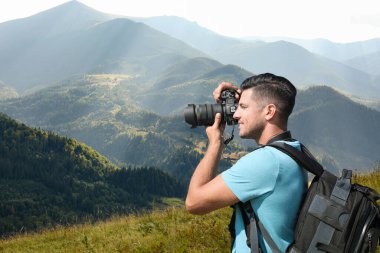 Photographer taking picture of beautiful mountains with professional camera