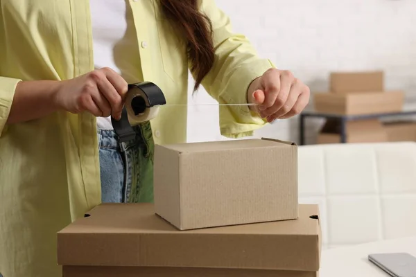 Seller packing cardboard box in office, closeup