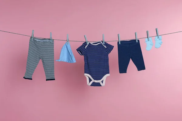 Different Baby Clothes Drying Laundry Line Pink Background — Stok fotoğraf