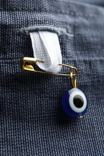 Evil eye safety pin on clothing, closeup