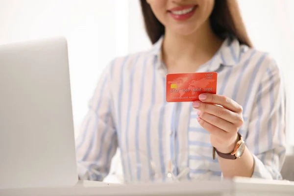 Woman with credit card using laptop for online shopping, closeup