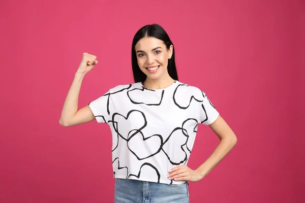 Strong woman as symbol of girl power on pink background. 8 March concept