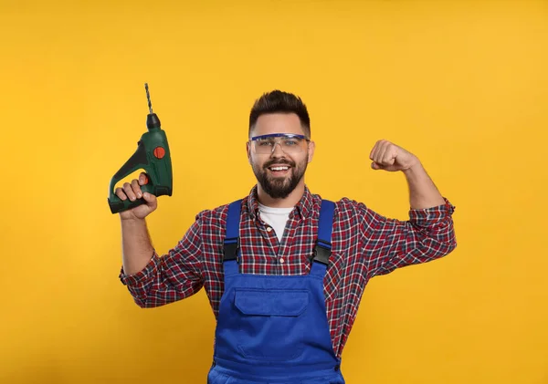 Jovem Trabalhador Uniforme Com Broca Energia Fundo Amarelo — Fotografia de Stock