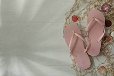 Tahta arka planda parmak arası terlikleri olan düz kompozisyon, metin için boşluk. Plaj nesneleri