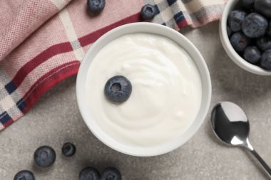 Bowl with delicious yogurt and blueberries on grey table, flat lay