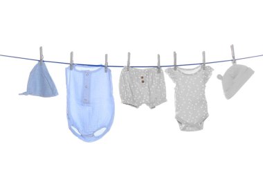 Different baby clothes drying on laundry line against white background