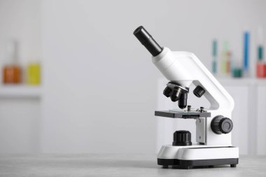 Modern medical microscope on grey table in laboratory, space for text