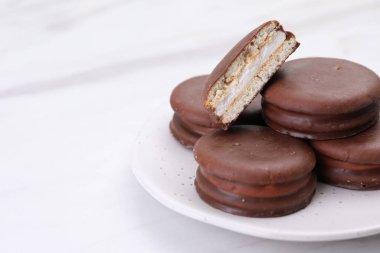 Saucer with delicious choco pies on white table, closeup. Space for text