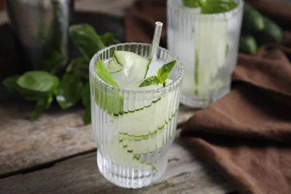 Refreshing cucumber water with basil on wooden table