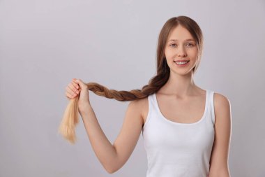 Sağlıklı, açık gri arka planda örgülü saçları olan genç bir kız.