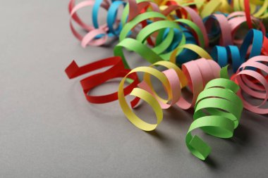 Colorful serpentine streamers on grey background. Space for text