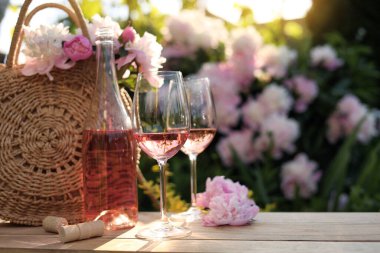 Şişe ve gül şarabı bahçedeki ahşap masada güzel şakayıkların yanında.