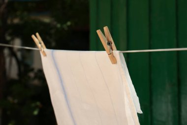 Washing line with clean laundry and clothespins outdoors, closeup