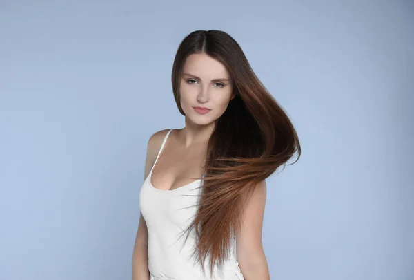 Young woman with strong healthy hair on light blue background