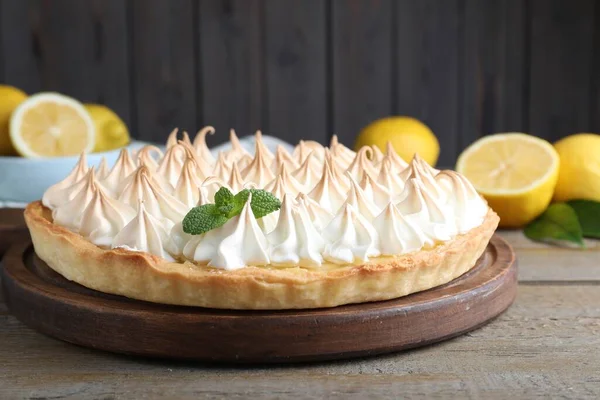 Delicious lemon meringue pie decorated with mint on wooden table